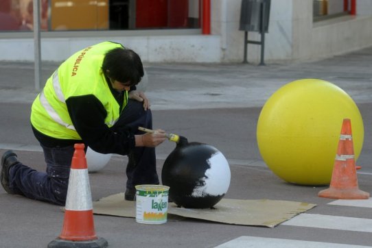 Un operari de Via Pública pintant una de les boles