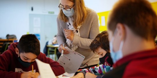 Una auxiliar de conversa amb alumnes a una aula de l'escola Sant Esteve.